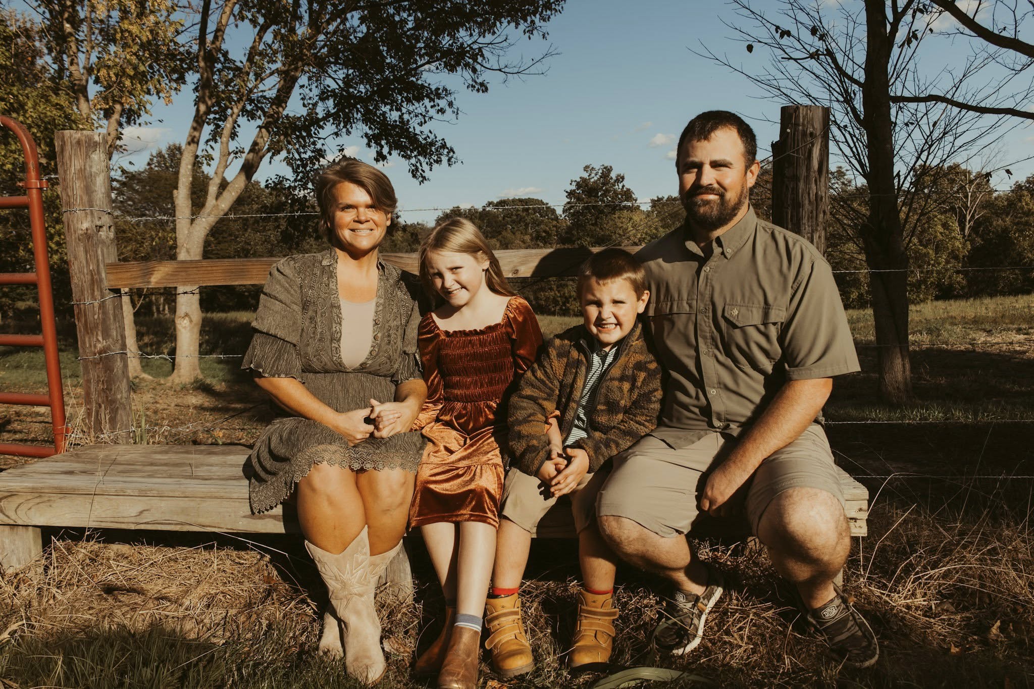 The Flamm family — Megan, her husband, and their two children sitting on a wooden bench outdoors in Anna, IL